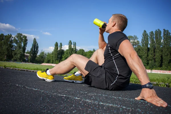 Attractive young male runner is very thirsty — Stock Photo, Image