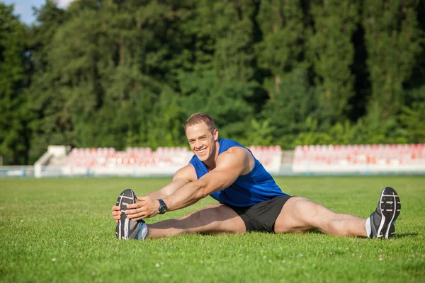 Atractivo corredor masculino joven está haciendo ejercicio antes de correr — Foto de Stock