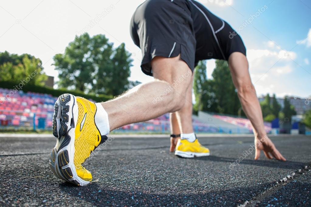 Young male runner at starting line before race