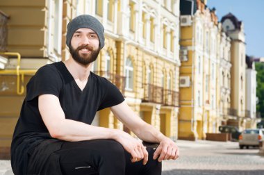 Attractive young hipster guy is having rest in city