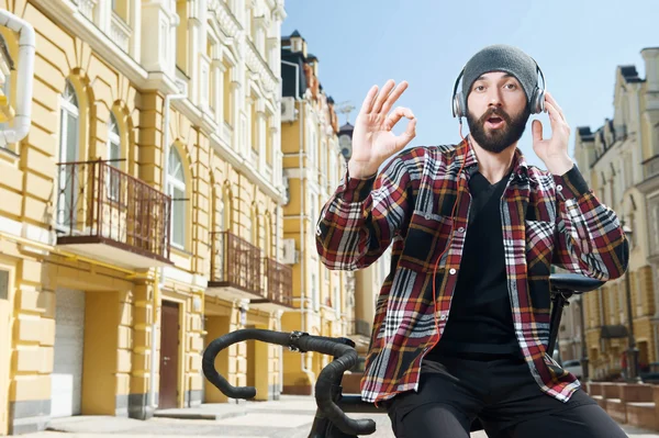 Cheerful young cyclist with headphones and cap — Stockfoto