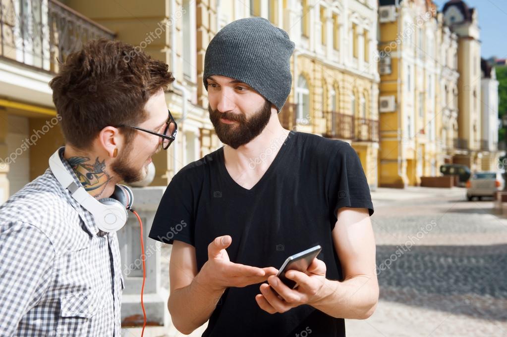 Attractive young hipster guys are having conversation on street