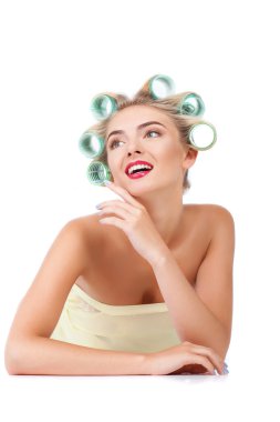 Cheerful young housewife with rollers is relaxing