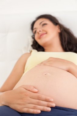 Cheerful healthy pregnant woman is relaxing in bedroom