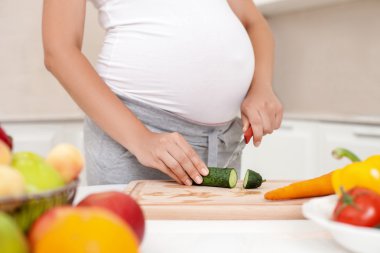 Genç hamile kadın mutfakta bir salata çatalı