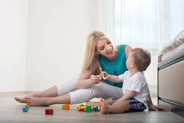 Jovem mãe alegre está brincando com seu filho — Fotografia de Stock