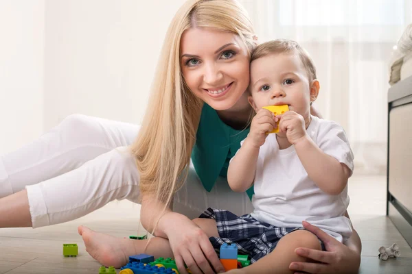 Vrolijke jonge moeder speelt met haar baby — Stockfoto