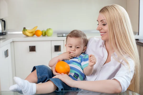 Schöne junge Mutter mit ihrem Kind in der Küche — Stockfoto