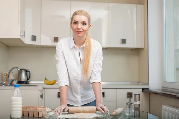 Hermosa joven ama de casa está horneando en la cocina — Foto de Stock