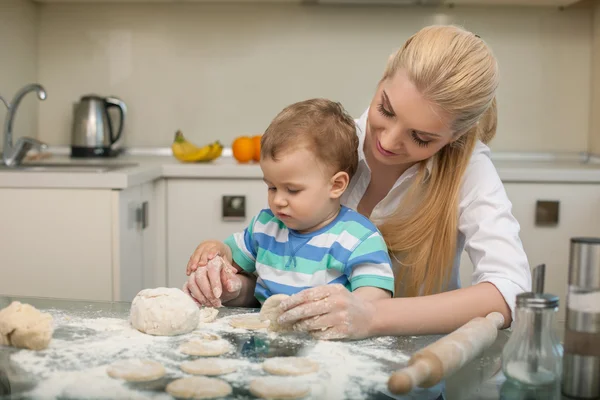 Pretty young housewife is cooking with her child — Stock Photo, Image