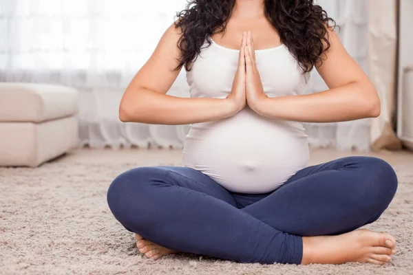 Young expectant mother is exercising in room — Stok fotoğraf