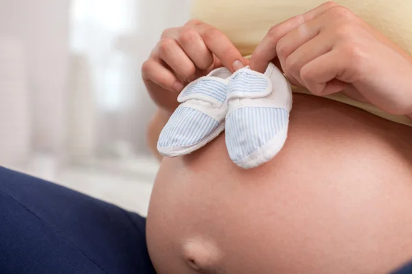 Young healthy pregnant woman is dreaming with small shoes — Φωτογραφία Αρχείου