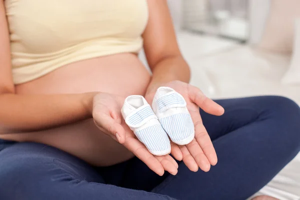 Young expectant mother is playing with baby booties — Stock Photo, Image