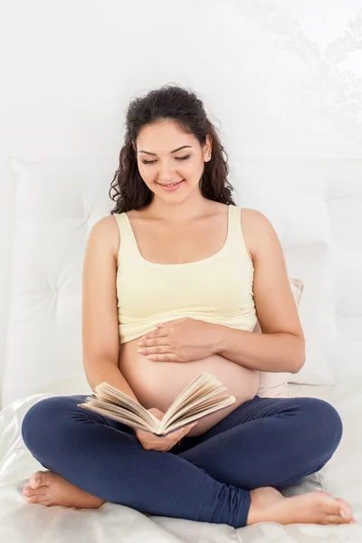 Cheerful young pregnant woman is resting in bedroom — Zdjęcie stockowe