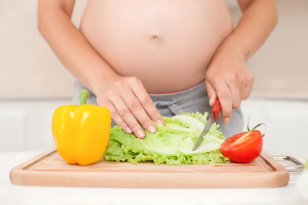 Joven madre embarazada saludable está cocinando en la cocina —  Fotos de Stock
