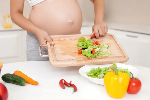 Mujer embarazada joven está cocinando alimentos saludables —  Fotos de Stock