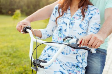 Young loving couple is riding bicycle in park