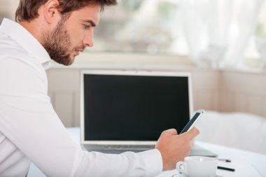 Attractive young businessman is messaging to his partner