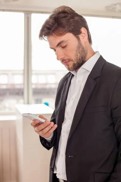 Attractive young man in suit is using telephone — Stock Photo, Image