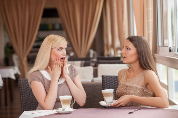 Guapas chicas jóvenes están chismeando en la cafetería —  Fotos de Stock