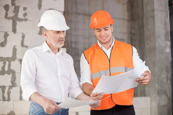 Equipe de construção alegre está trabalhando no plano de construção — Fotografia de Stock