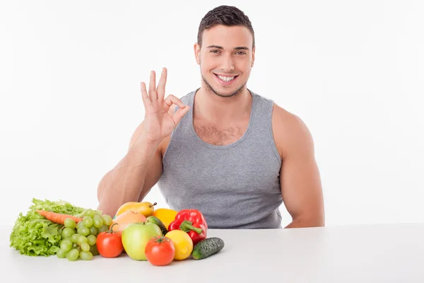 Joyeux jeune homme mange des aliments sains et des gestes — Photo