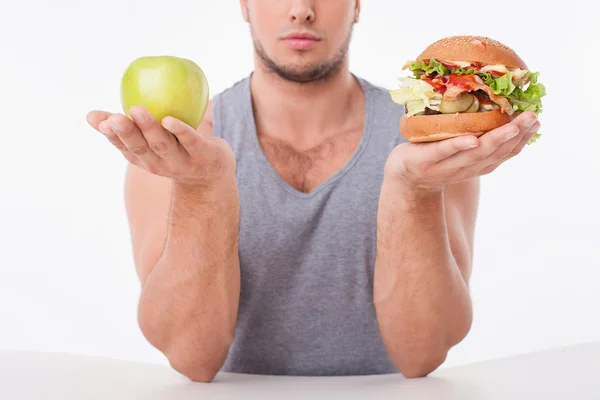 Young fit guy is choosing between healthy and unhealthy food — ストック写真