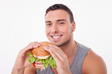 Cheerful young sportsman is enjoying unhealthy food