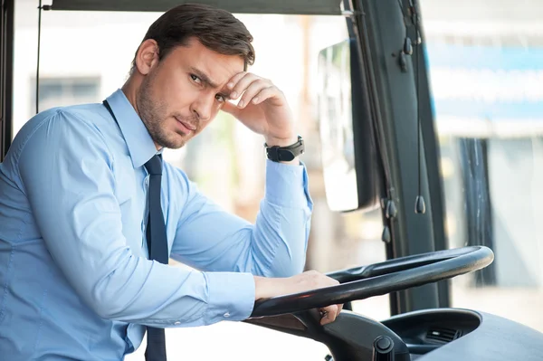 Handsome young driver is sitting at steering wheel