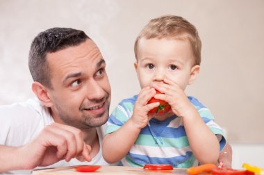 Handsome young father is feeding his kid clipart