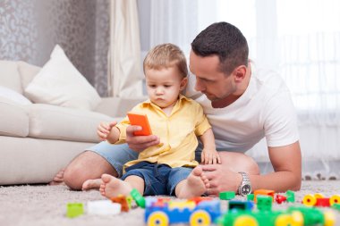 Handsome father is acquainting his child with modern technologies