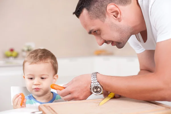 Cheerful young father is feeding his little child — Stock Photo, Image
