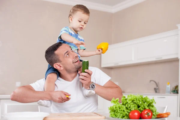 Cheerful man and his kid are cooking healthy food — Zdjęcie stockowe