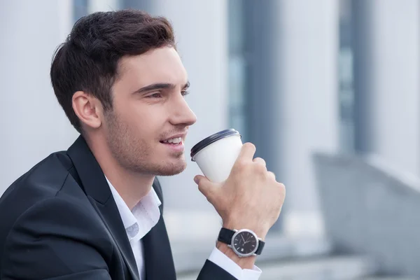 Handsome young businessman is enjoying hot drink outdoors — 图库照片