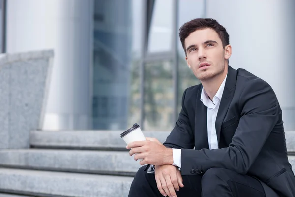 Bello giovane uomo sta riposando vicino al suo ufficio — Foto Stock