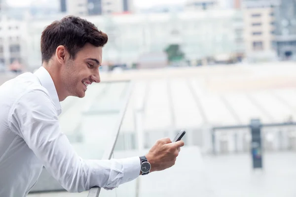 Cheerful young man is using modern technology — Stock Photo, Image