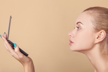 Pretty young blond girl is checking her appearance