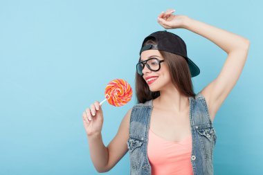 Cheerful young styled woman is posing with candy