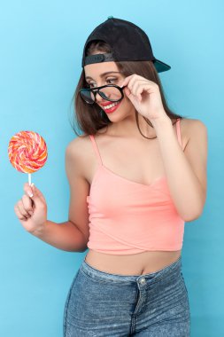 Pretty young styled girl is enjoying sweet lollipop