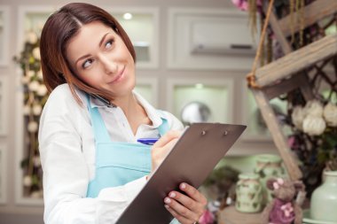 Beautiful young florist is communicating on the telephone