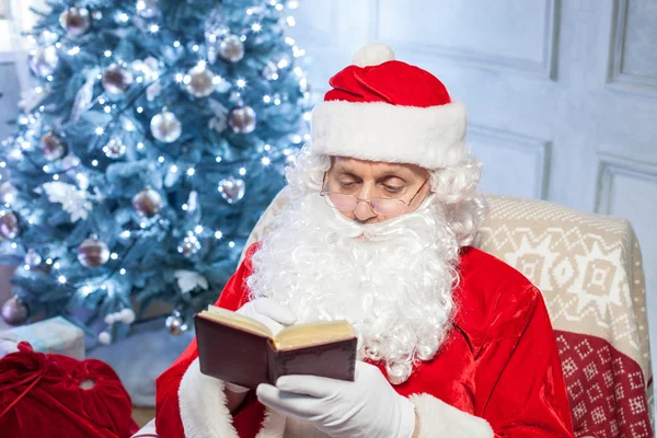 Cheerful Santa Claus is resting near a holiday tree — Stok fotoğraf