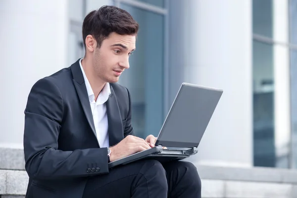 Giovane uomo d'affari allegro sta lavorando con notebook — Foto Stock