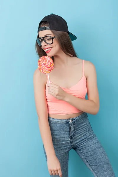 Cheerful young hipster girl is eating lollipop — Stok fotoğraf