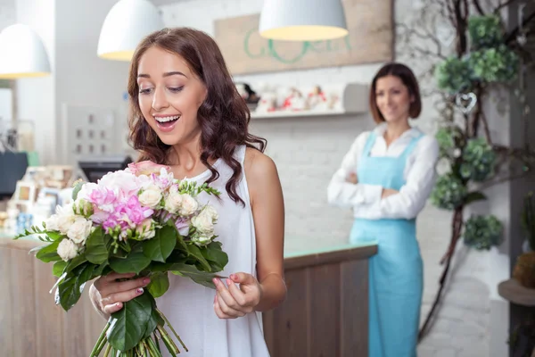 Cheerful young girl is buying a bouquet in shop — Stock Photo, Image