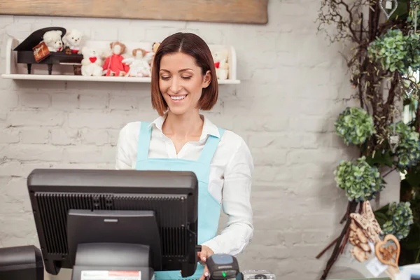 Cheerful young saleswoman is working in flower shop — 图库照片