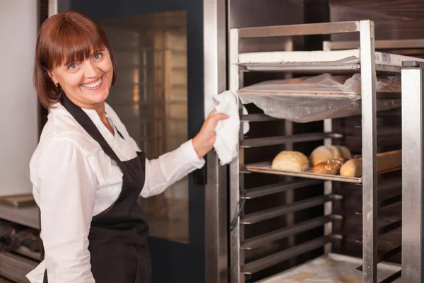 Cheerful saleswoman is working in bakery with joy — Stock Photo, Image