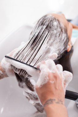 Beautiful young woman is getting a hairwash in salon
