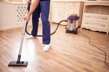 Cheerful young cleaner is doing housework with joy