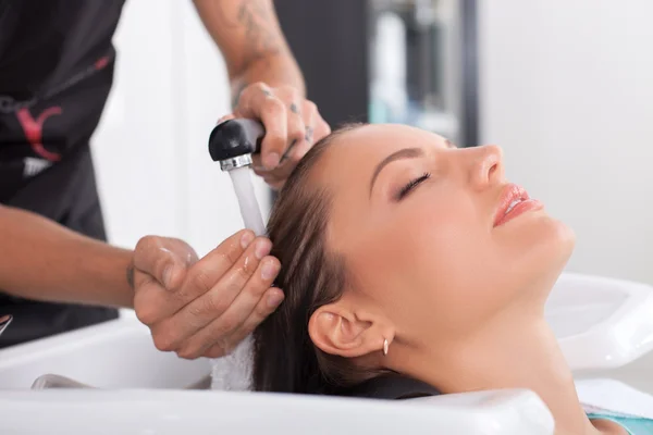 Beautiful young woman is caring of her hair in salon — 스톡 사진