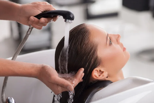 Гарненька молода жінка омиває волосся перукарем — стокове фото